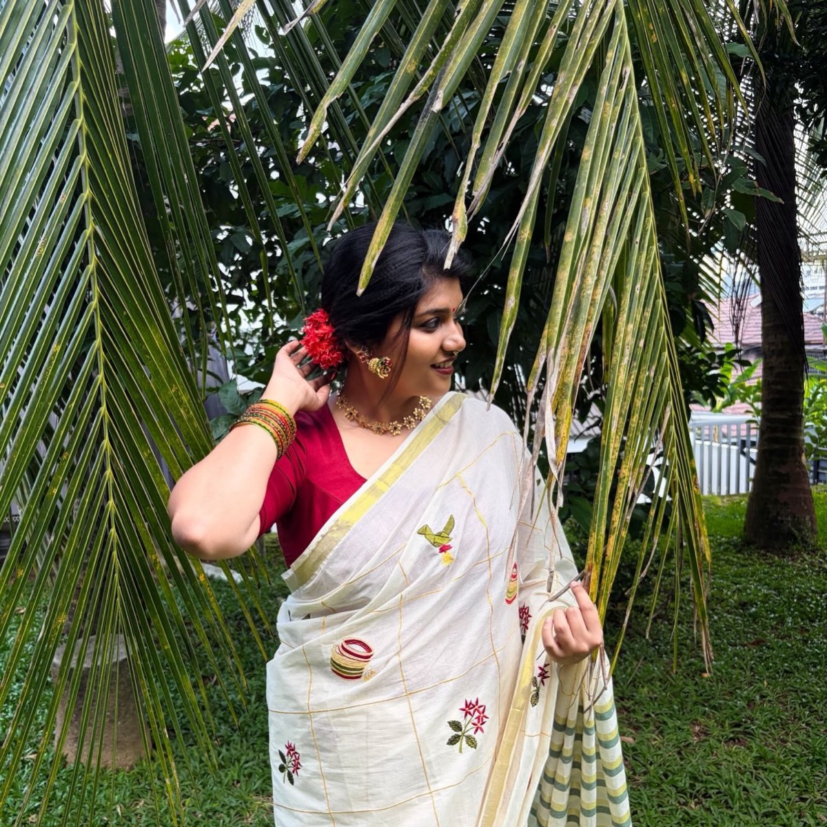 A client in a white saree with red flowers in her hair