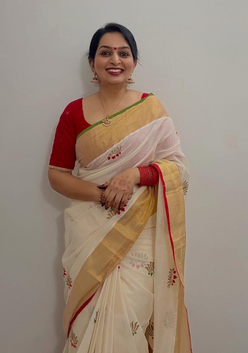 A client in a cream and gold saree with a red blouse