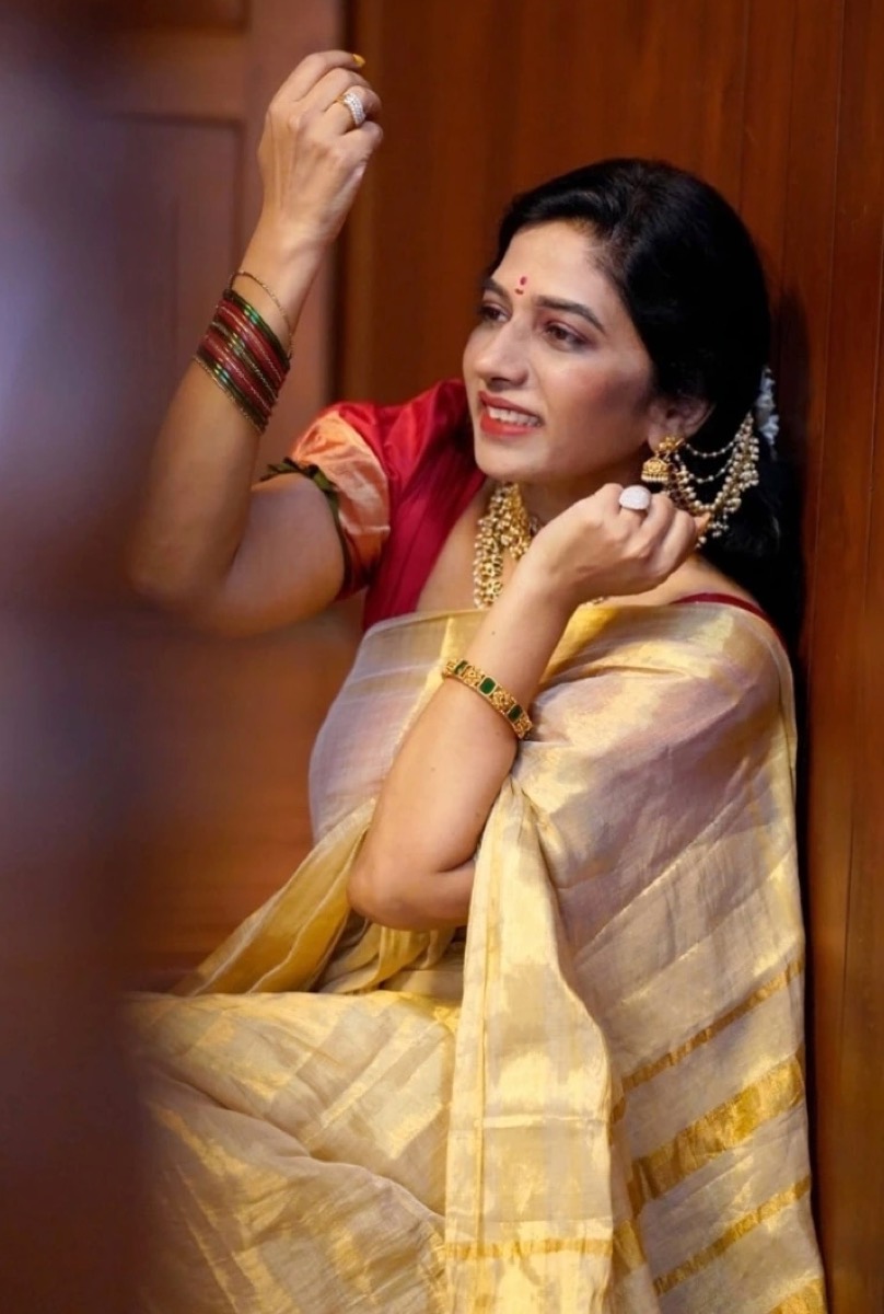 A client in a gold saree fixing her earrings