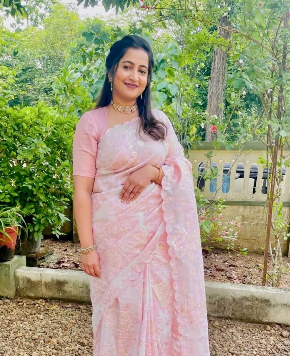 A client in a soft pink saree in a garden