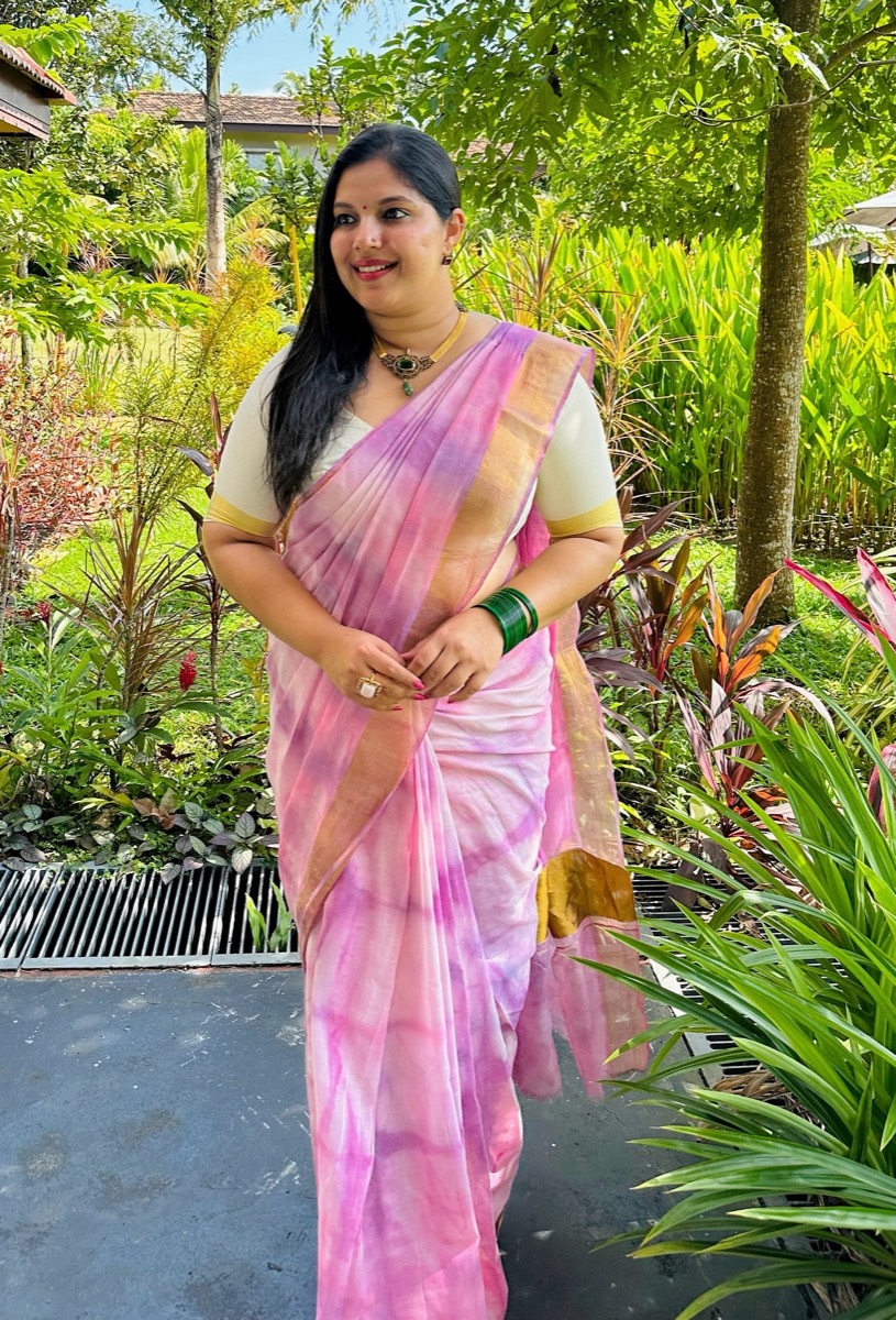 A client in a pink and lilac saree in a garden