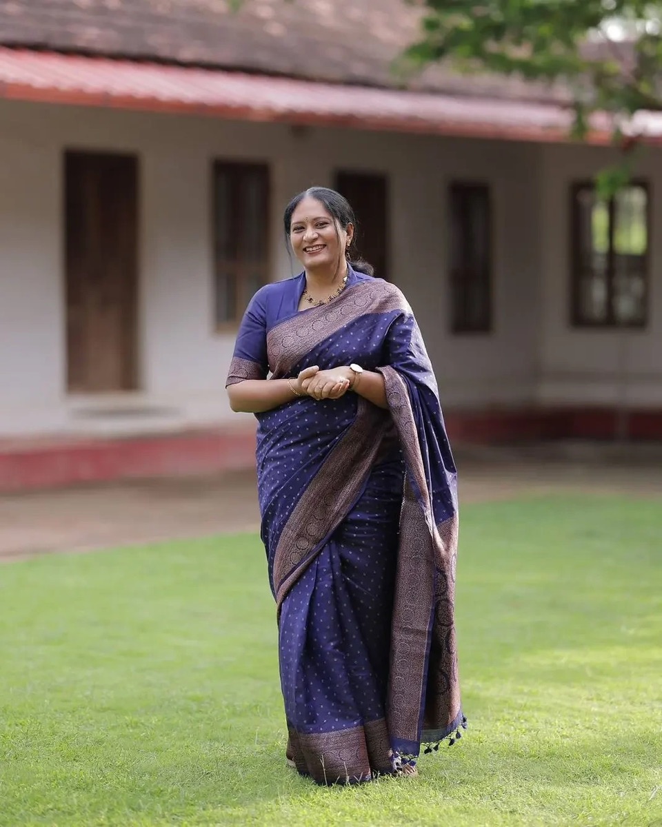 A smiling client in a navy silk saree with a woven border