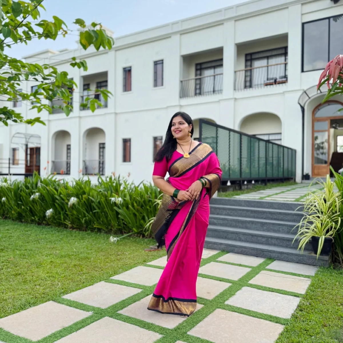 A client in a pink saree with a gold border on a lawn