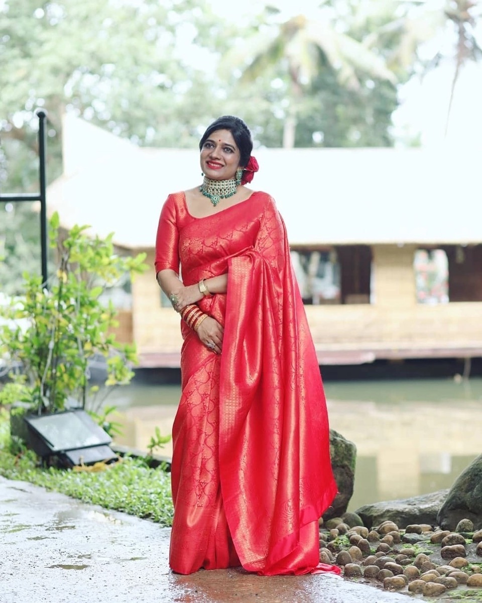 A client in a red silk saree beside the backwaters